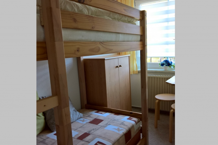 Schlafraum mit Hochbett und Polsterliege, Kommodenschrank und Tisch mit 2 Hockern - das Fenster zeigt auch nach hinten zur Sitzecke