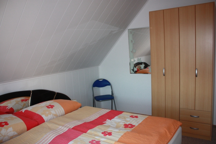 Schlafzimmer mit Doppelbett und Kleiderschrank - auch für ein Kinderbett ist Platz vorhanden
