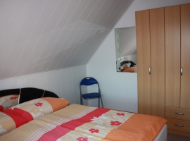 Schlafzimmer mit Doppelbett und Kleiderschrank - auch für ein Kinderbett ist Platz vorhanden