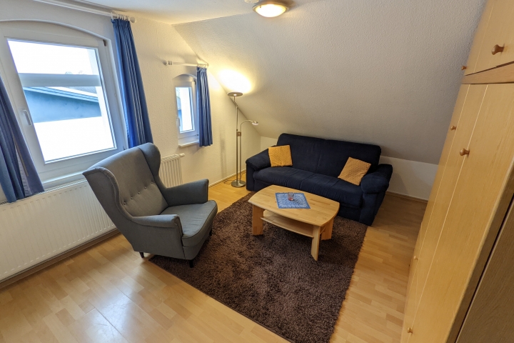 Ferienwohnungen im Haus Eintracht | Wohnzimmer mit Sitzgruppe und rechts das (geschlossene) Doppelschrankbett