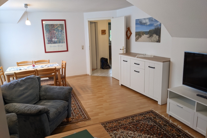 Wohnzimmer mit Essplatz und Blick auf die Tür zum Flur und Küche