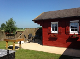 Blockhaus 2: Blick auf die Terrasse mit Grill und Gartenmöbeln