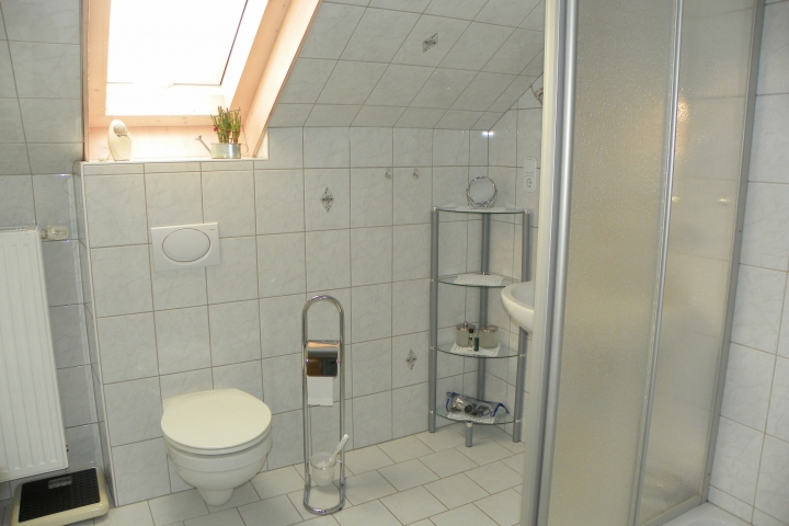 helles Duschbad mit WC und Waschbecken. Handtücher werden gestellt.