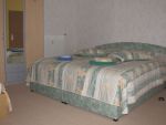 Schlafzimmer mit Doppelbett, Schrank, Nachtschränkchen und am linken Rand eine Aufbettung