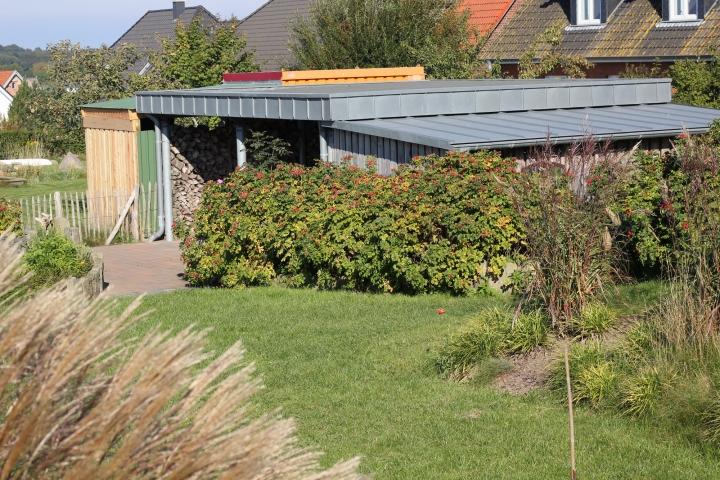 Blick auf Carport und Fahrradschuppen vom Garten