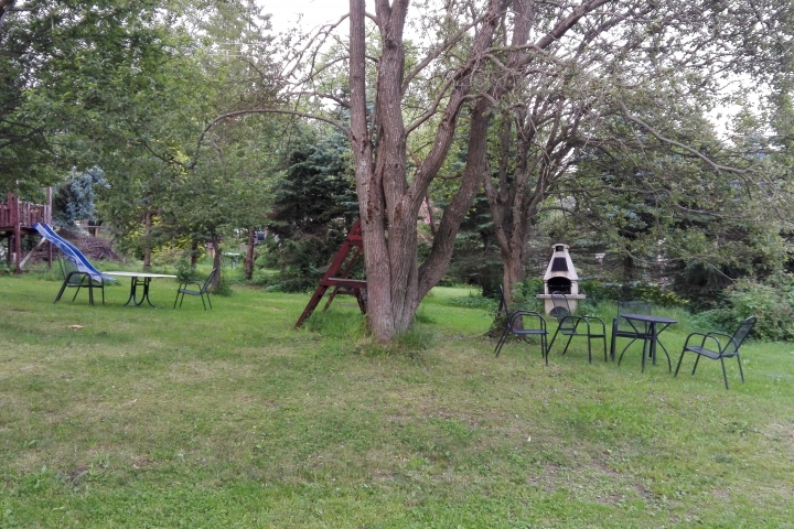 Garten mit Außensteingrill und Gartenmöbeln.