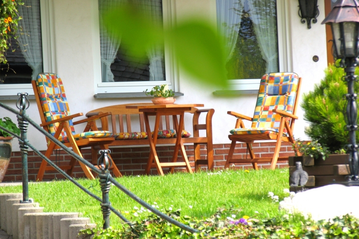 Ansicht der überdachten Terrasse der Wohnung mit dazugehörigen Holzgartenmöbeln.
