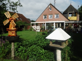 Blick auf den Garten und auf die Ferienwohnung mit überdachten Balkon mit Turmspitze.