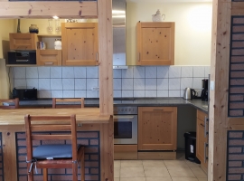 Die Küche ist durch den Tresen vom Raum abgeteilt, hat einen vollwertigen Herd und eine Spülmaschine