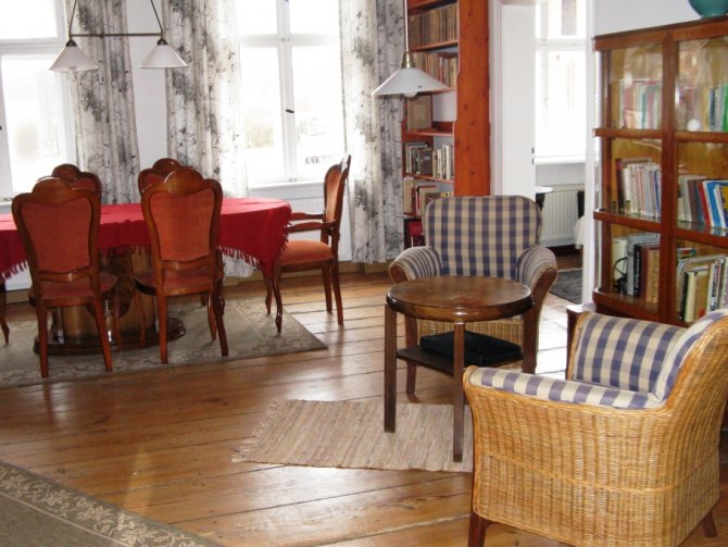 Ferienwohnungen Hof Luisenau | Wohnzimmer mit einem großen Esstisch und einer kleinen Lesebibliothek.