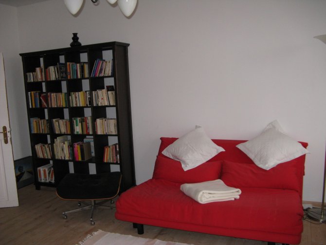 Wohnzimmer mit TV, Couch, Sitzecke und kleiner Lesebibliothek.