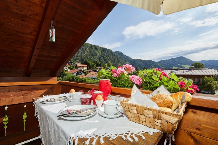 Auf dem überdachten Balkon das Frühstück geniesen und den Sonnenaufgang beobachten - Blick zum Dorf mit Bergpanorama
