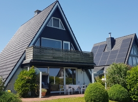 Rückansicht mit Terasse, Strandkorb und Gartenmöbeln.