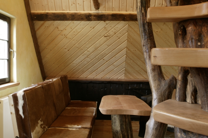 Die Holzwendeltreppe führt zum Schlafboden, das Sofa kann umgeklappt werden