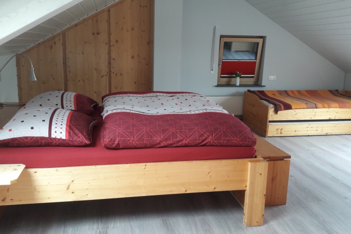 Schlafzimmer mit Doppelbett und ausziehbarem Bett sowie Kinderbett (Dachgeschoss)