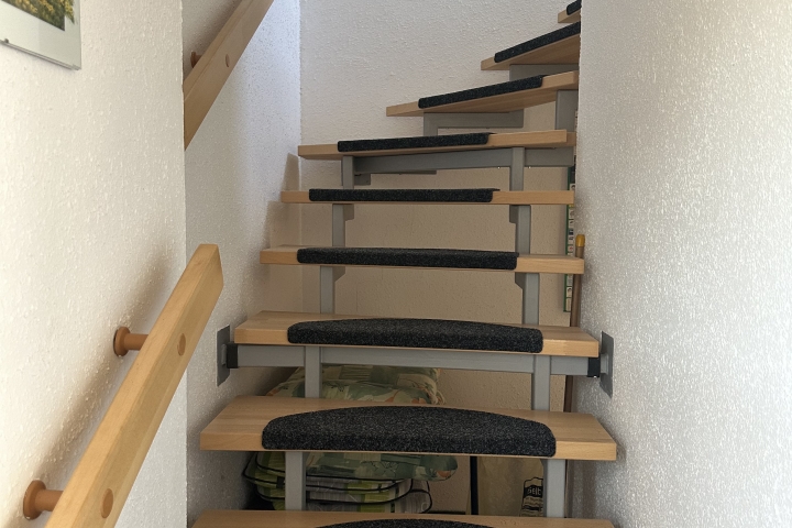Treppenaufgang von der Wohnküche zu Wohnzimmer, Schlafkammer, Dusche und WC. Dahinter sieht man die Stuhlauflagen für den Aussenbereich.