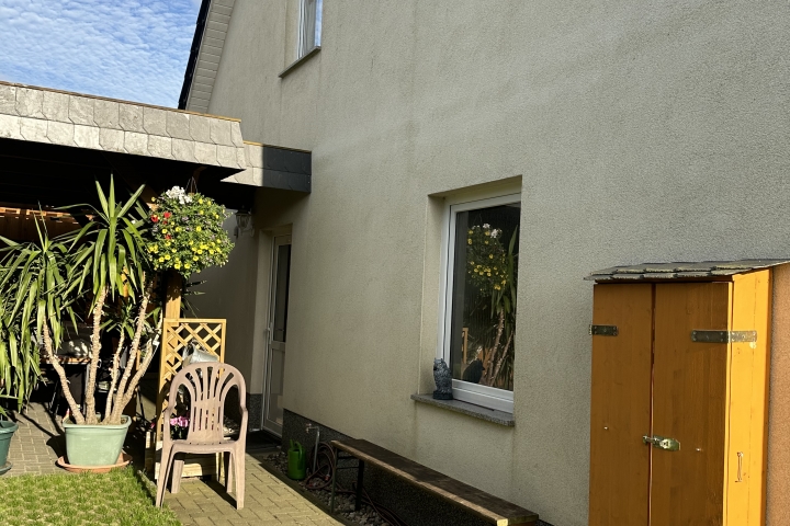 Sie sehen über und hinter der Garage die Fenster und die Eingangstür der Wohnung B 