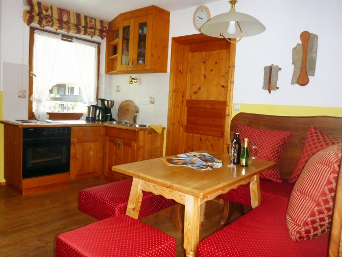 Ferienwohnung Haus in der Loferau | heller wohnraum mit gemütlicher Polstersitzgruppe Flachbild TV, helle Einbauküche aus Holz und Südbalkon