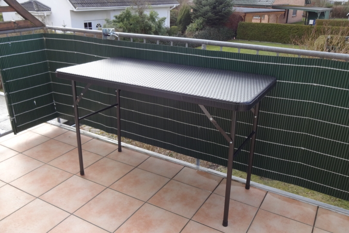 Balkon mit Tisch, dazu vier Stühle und Sonnenschirm