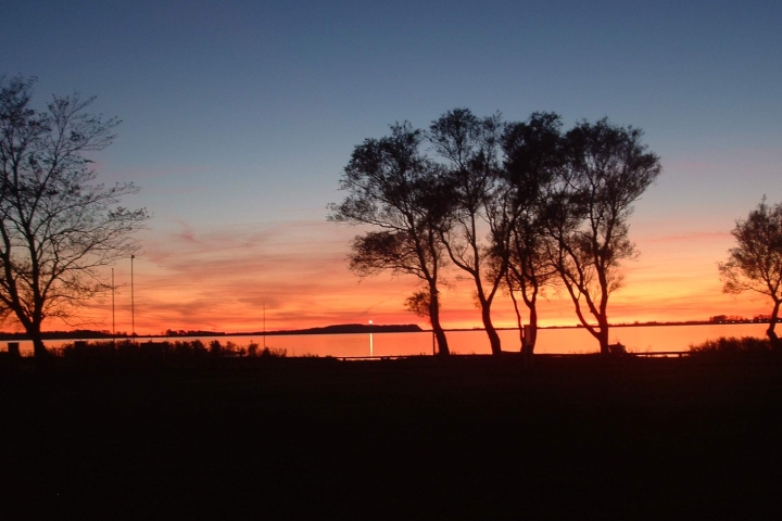 Sonnenuntergang mit Blick auf Hiddensee mit dem Leuchtturm am Dornbusch