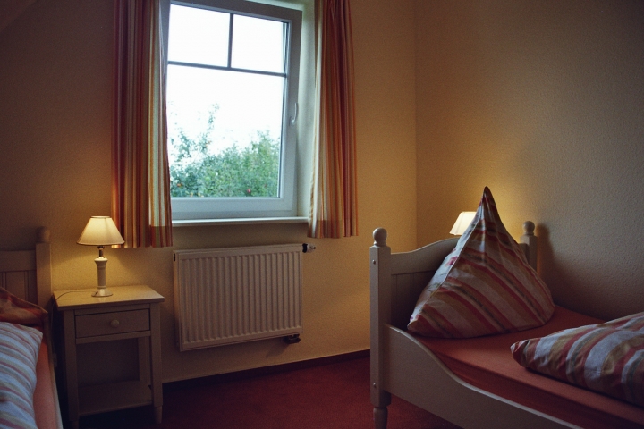 Das dritte Schlafzimmer mit zwei cremefarbenen Landhausbetten und Nachtkonsolen.