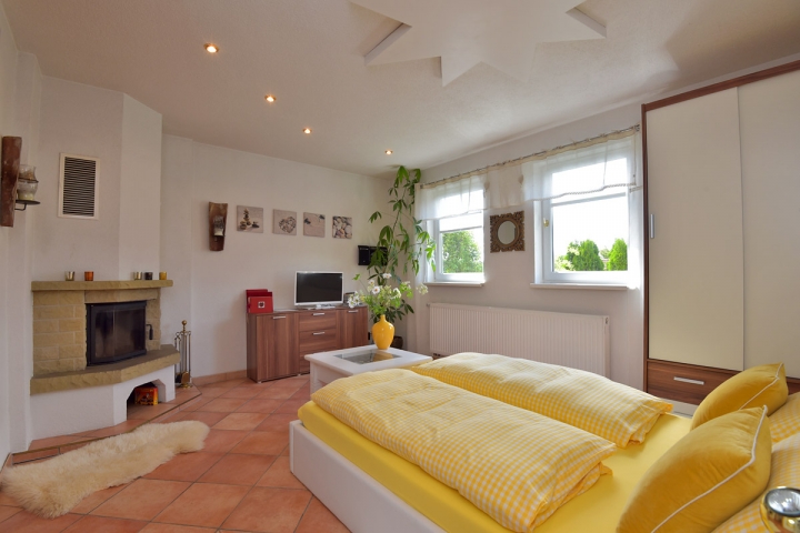 Schlafbereich mit Doppelbett, TV und Kamin