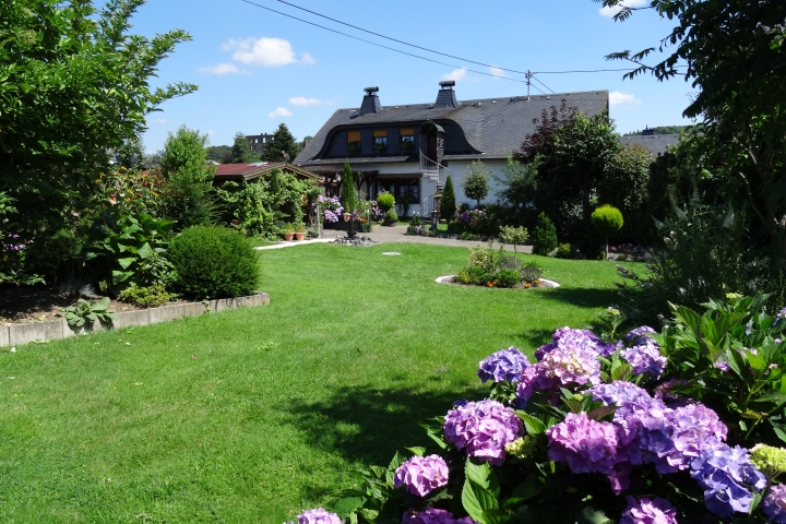 Eifel Ferienwohnungen Decker in Ulmen, Blick vom Gästegarten auf Haus und Burgruine.