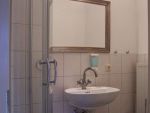 Helles Badezimmer mit weißen
Kacheln und Antrazit-Fußbodenfliesen. Dusche, Wc
und Waschbecken.