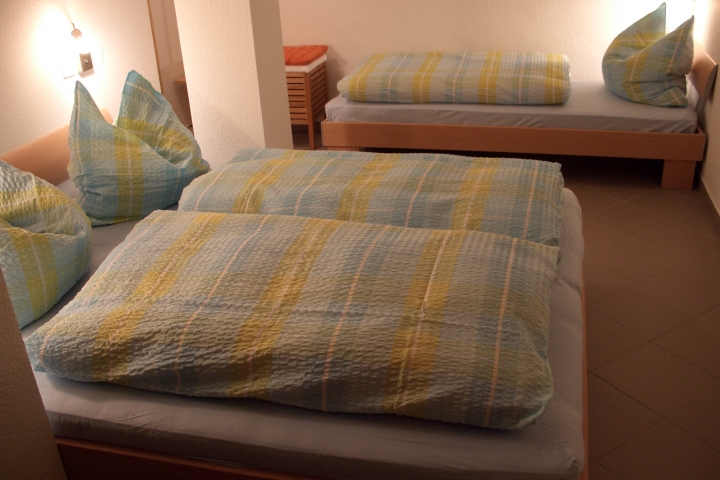 Schlafzimmer mit 3 Betten,
Schrank, Hockern und Garderobe