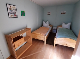 Im Schlafzimmer sind 2 Einzelbetten, Kleiderschrank, Nachttisch und Regal.