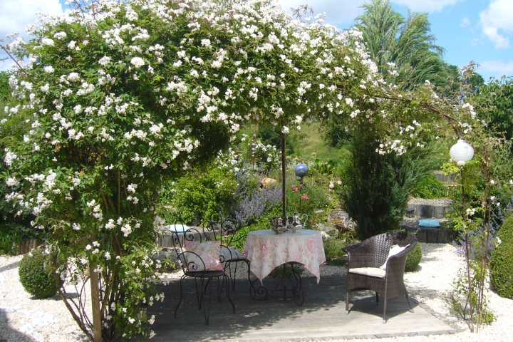 Der romantische Rosenpavillion lädt ein zum Verweilen, schon in der Morgensonne bei Vogelkonzert,ab Mittag bieten die überbordenden Kletterrosen angen