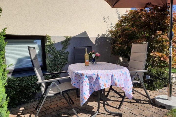Sitzecke im Freien mit Tisch und Relaxstühle, Sonnenschirm, Grill auf Wunsch