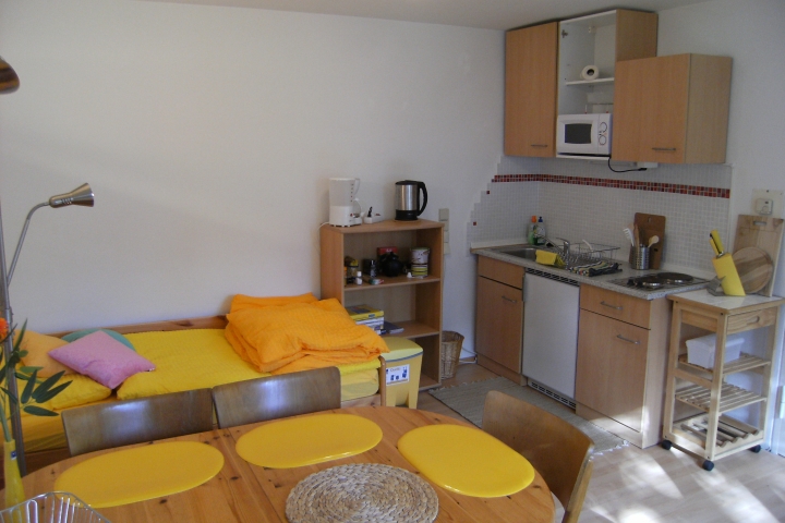 Gelbes Zimmer mit hinterem Bett (das mit der Ausziehmatratzenschublade) und Küchenzeile sowie Tisch