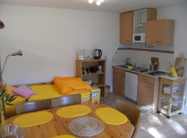 Gelbes Zimmer mit hinterem Bett (das mit der Ausziehmatratzenschublade) und Küchenzeile sowie Tisch