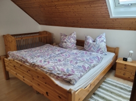Schlafzimmer mit Doppelbett und feststehendem Kinderbett.
