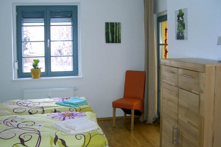 Bett 1,80 m x 2,00 m mit getrennten Matratzen.Die Tür rechts führt auf eine kleine Loggia mit Blick in den Garten.