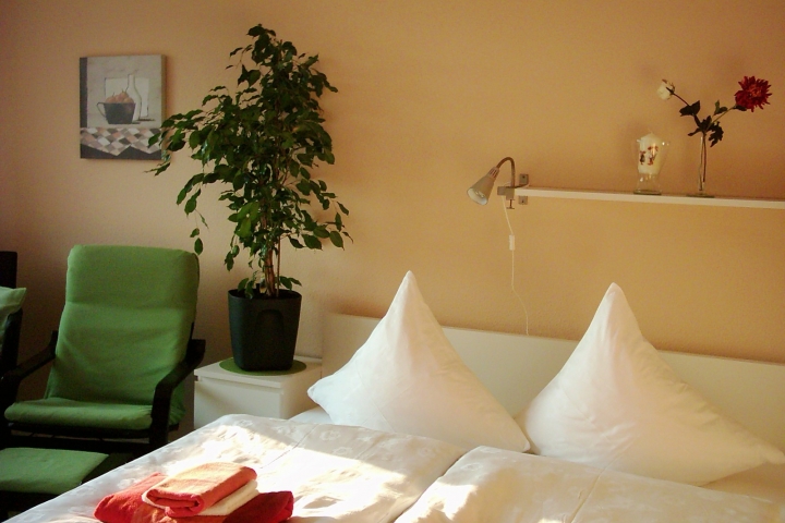 Blick aus Richtung Flur in den Wohn-/Schlafraum. Über dem Bett befindet sich ein Deckenventilator. ©