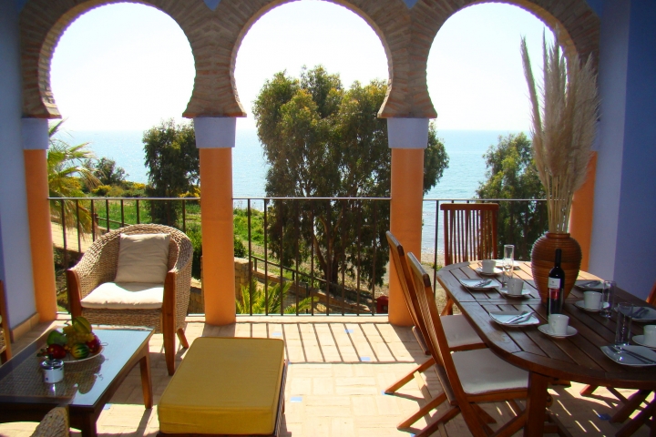 überdachte Terrasse mit Blick auf Garten und Meer