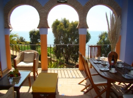 überdachte Terrasse mit Blick auf Garten und Meer