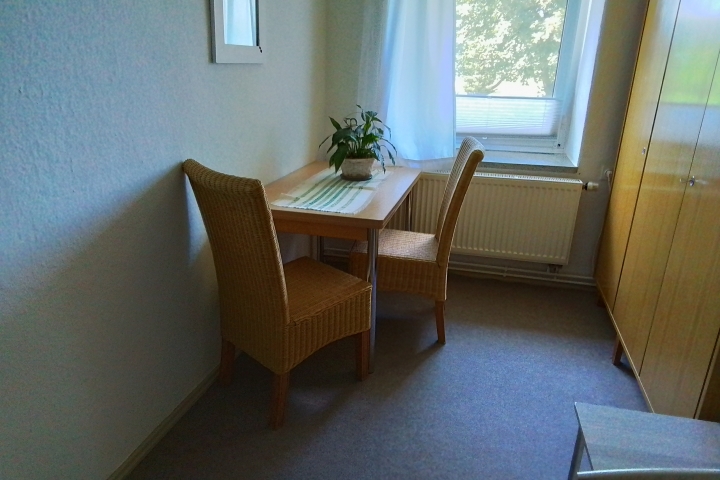 Zweites Schlafzimmer mit Tisch, zwei Stühle und Schrank in Fewo 2