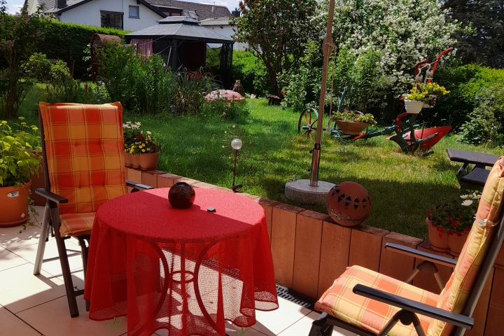 Terrasse mit schönem Blick auf die Liegewiese mit Blumen und bunten Sträuchern