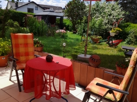 Terrasse mit schönem Blick auf die Liegewiese mit Blumen und bunten Sträuchern