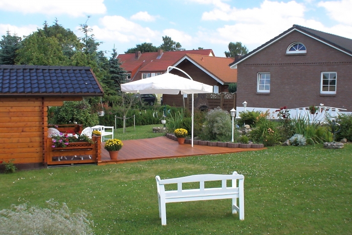 Ihre Terrasse - Hinter dem Sonnenschirm, sehen Sie den aufgebauerten Grillofen.