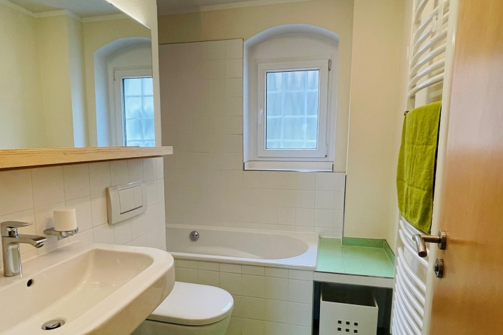 Bad mit großem Waschbecken, Fenster und Wanne inklusive Duschbereich