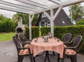 Überdachte Terrasse mit Grill und Sitzgruppe