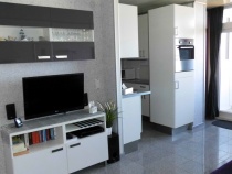 Sideboard mit TV und 2.1-Heimkinoanlage und Hängeschrank, Blick auf Küche und Balkontüre