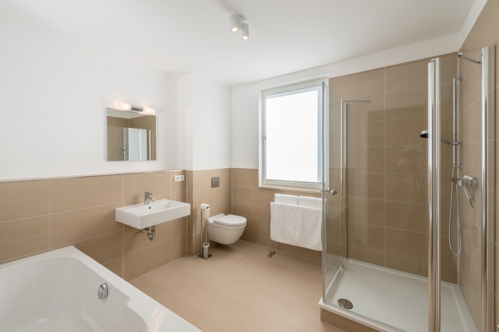 Großes, helles Badezimmer mit Badewanne, Dusche und WC