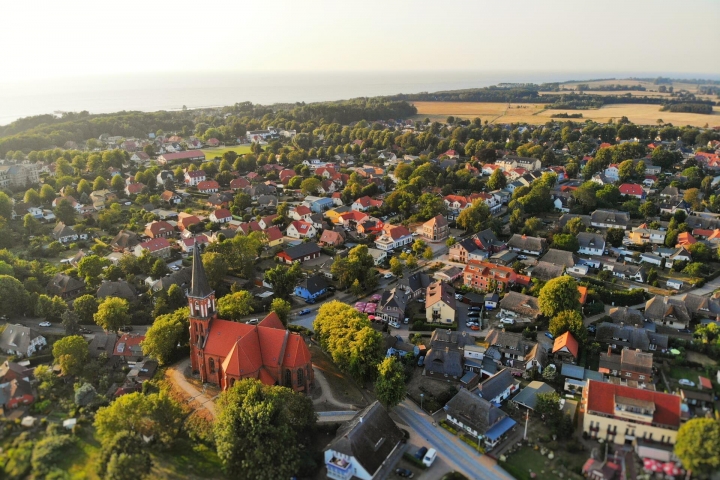 Blick vom Kirchturm links der Bodden und die Ostsee am Horizont, dazwischen versteckt liegt das Runenhaus, nicht weit zur Ostsee oder Bodden