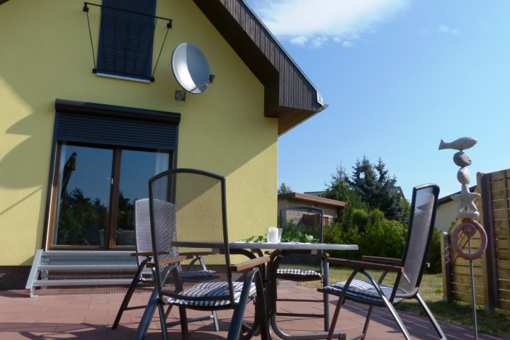 Die sonnige Terrasse mit Gartenmöbeln, Grill und im Sommer mit Sonnenschirm