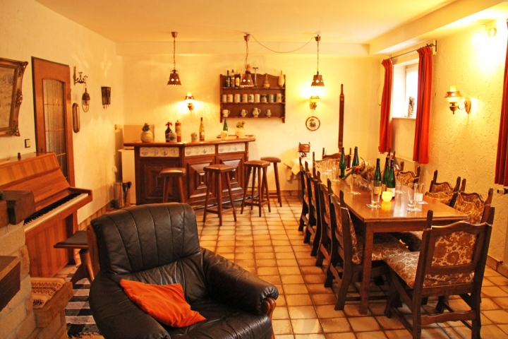 Teil der Partykeller mit Bar, Esstisch für 16 Personen, Klavier und offene Kamin